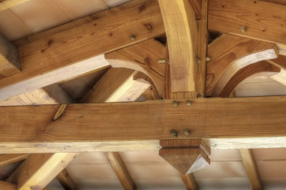 Intérieur d'une charpente en bois avec poutres apparentes et assemblages traditionnels
