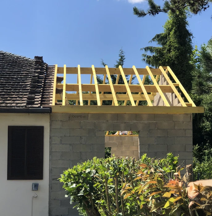 Chantier de construction résidentielle en extérieur montrant l'extension d'une maison existante