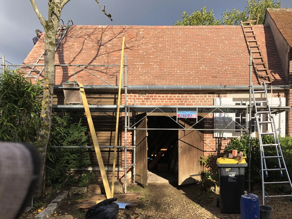 Chantier de rénovation extérieur d'une maison en briques rouges avec ouvriers sur échafaudage