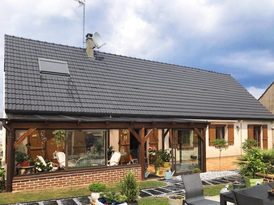 Toiture résidentielle moderne avec tuiles ardoise grises, cheminées en brique, lucarne avec fenêtre et structure murale en blocs béton